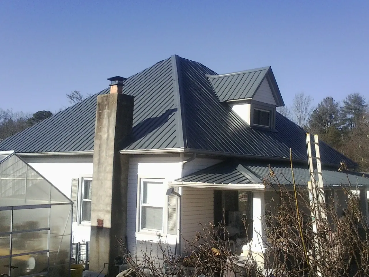 Dark blue standing seam metal roof on a white farmhouse with dormer — Slate & Tile Roof Repair by Roofing Brothers in Timber