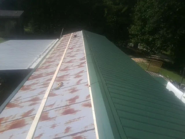 Old rusted panels beside newly installed green metal roofing — Wind Damage Roof Repair by Roofing Brothers in Timber