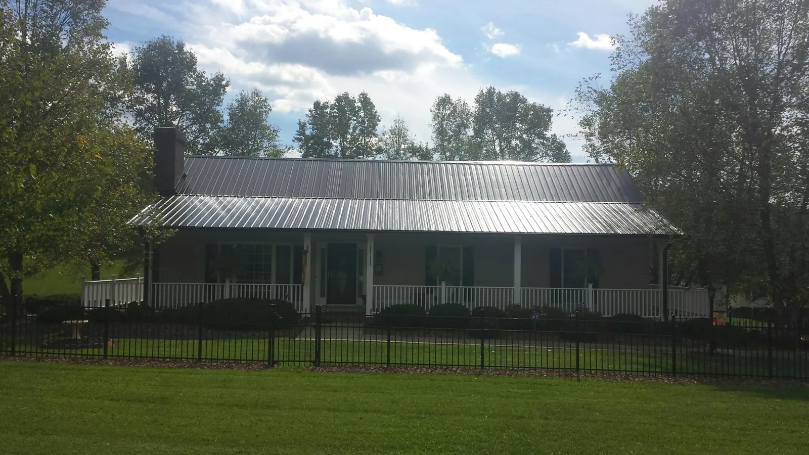 Gray metal roof on a brick ranch with a full width front porch — Gutter Guard Installation work by our crew in Timber